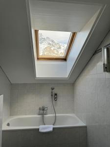 a bathroom with a bath tub with a window at Hotel Residence in Grindelwald