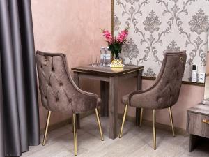 uma mesa com duas cadeiras e uma mesa com um vaso de flores em Stela Hotel em Shymkent