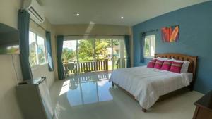 um quarto com uma cama com almofadas cor-de-rosa e uma varanda em Lay Back Villa C1with kitchen & High Speed Internet em Cidade de Krabi