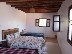 a bedroom with a bed and a couch and windows at Dar Lala Zhour in Aïn Bouchrik