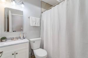 a white bathroom with a shower curtain and a toilet at Suite 2 on Southport 4 Queen Beds in Chicago