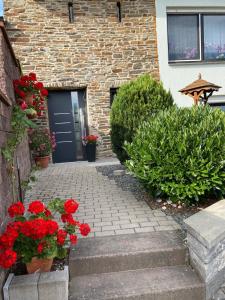 a brick building with a door and red flowers at Familie Moisil in Daun