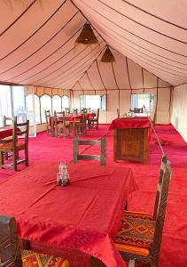 a tent with red tables and chairs in a room at Explore merzouga luxury camp in Merzouga