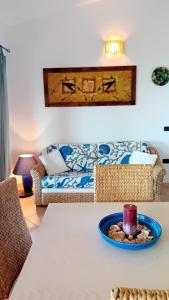 a living room with a couch and a table with a candle at VILLETTA TRAMONTO - INFINITYHOLIDAYS in Costa Paradiso