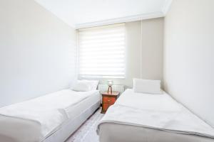 twee bedden in een kamer met een raam bij Cozy Flat with Balcony 10 min to Hadrian Gates in Antalya