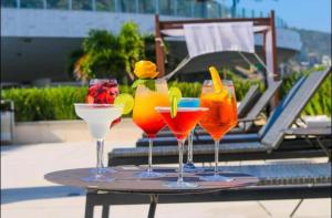 four drinks sitting on a table next to a pool at Hotel Nacional Rio de Janeiro in Rio de Janeiro