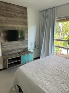 Apartamento Villas do Pratagy في ماسيو: غرفة نوم بسرير وتلفزيون بشاشة مسطحة