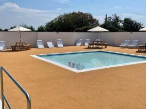 a swimming pool with chairs and tables and umbrellas at 25. Valencia in Selsey