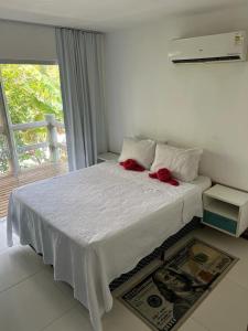 Apartamento Villas do Pratagy في ماسيو: غرفة نوم عليها سرير ووردين حمر