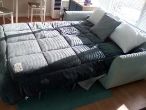 a couch with a blanket on top of it at 25. Valencia in Selsey +17 photos