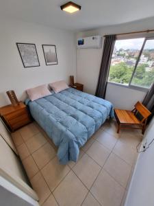 um quarto com uma cama azul e uma janela em Alójate en este espacioso departamento mensual em Córdoba