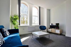 ein Wohnzimmer mit einem blauen Sofa und einem TV in der Unterkunft FREE PARKING - Beautiful 2-BR Flat in Manchester in Manchester