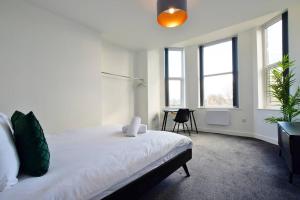 Schlafzimmer mit einem Bett, einem Schreibtisch und Fenstern in der Unterkunft FREE PARKING - Beautiful 2-BR Flat in Manchester in Manchester