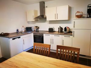 a kitchen with white cabinets and a table and chairs at Ferienwohnung am Waldpfad in Kaiserslautern