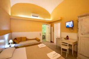 Cette chambre dispose d'un canapé, d'une table et d'une télévision. dans l'établissement Il Giardino di Tonia - Oplontis Guest House - Bed & Garden -, à Torre Annunziata