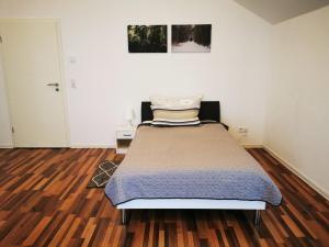 uma cama num quarto com piso em madeira em Ferienwohnung am Waldpfad em Kaiserslautern