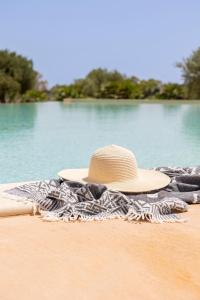 a straw hat sitting on a towel on a beach at Agua Green Resort in San Lorenzo