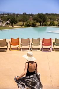 Una donna con un cappello seduta davanti alle sedie di Agua Green Resort a Reitani