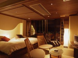 a bedroom with a bed and chairs and a television at Hatori in Kaga