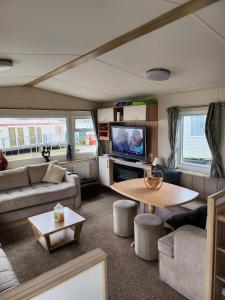 a living room with a couch and a table and a tv at Lovely 8 Berth Caravan With Decking And Wifi In Yorkshire, Ref 71011ic in Tunstall