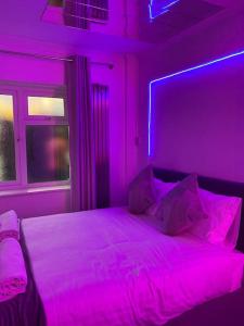 ein Schlafzimmer mit einem Bett mit violettem Licht in der Unterkunft Luxury Urban Hideaway with private hot tub in Croydon