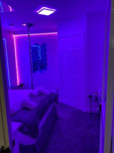 ein Schlafzimmer mit lila Lichtern und ein Bett in einem Zimmer in der Unterkunft Luxury Urban Hideaway with private hot tub in Croydon