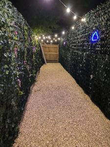 a fence with a wooden gate and flowers and lights at Luxury Urban Hideaway with private hot tub in Croydon