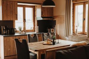 uma cozinha com uma mesa e cadeiras de madeira e uma cozinha com janelas em Oberwald Chalets 1 em Schotten