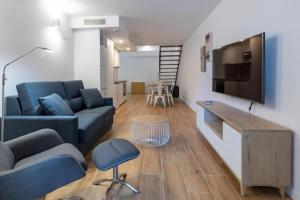 sala de estar con sofá azul y TV de pantalla plana en Duplex 6 pax 2 BTH, excelent area luxor, en Valencia