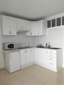 uma cozinha branca com armários brancos e um micro-ondas em Port Royale Los Cristianos em Los Cristianos