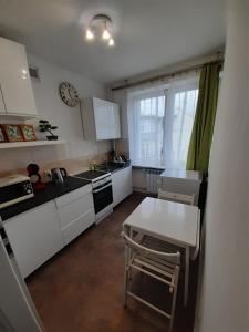 a kitchen with white cabinets and a table and a window at Sopot Center Saba Appartement in Sopot