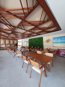 uma sala de jantar com mesas e cadeiras de madeira em Muro alto porto de galinhas Makia experience em Porto de Galinhas