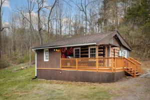a small house with a deck in a field at Creekside Cabin w Hot Tub, Fire Pit, Grill, WiFi! in Basye