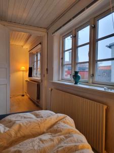 um quarto com uma cama e duas janelas em Rummeligt byhus i Allinge med værelse i stueplan og havkig em Allinge