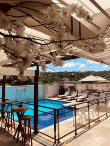 a patio with tables and chairs and a swimming pool at Bliss Hotel Vale do Café in Vassouras