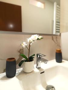a bathroom sink with a vase with flowers on it at Cernobbio Studio in Cernobbio
