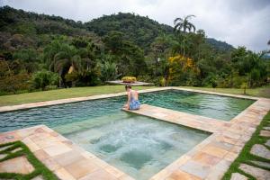 una donna seduta in una piscina d'acqua di Pousada Vilarejo do Quim a Tapiraí