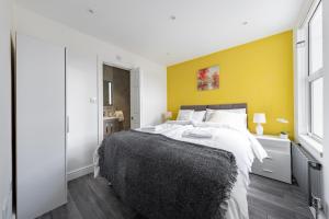 um quarto com uma cama grande e uma parede amarela em VitiLevu House em Southall
