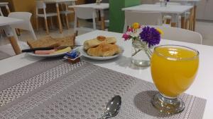 una mesa con un vaso de zumo de naranja y un plato de comida en Nómade Hostel mdz en Mendoza