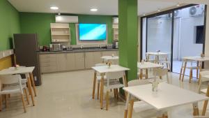 aula con mesas y sillas blancas y TV en Nómade Hostel mdz en Mendoza