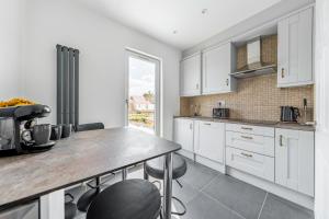 a kitchen with white cabinets and a table and chairs at VitiLevu House in Southall +4 photos