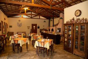 restauracja ze stołami i krzesłami oraz zegarem na ścianie w obiekcie Pousada Vilarejo do Quim w mieście Tapiraí