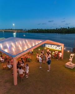 um grupo de pessoas sentadas sob uma tenda ao lado da água em BUGAN PAIVA RECIFE no Recife