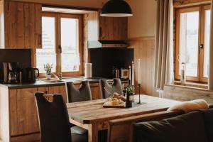 cocina con mesa de madera y sillas y cocina con ventanas en Oberwald Chalets Ferienhaus 3 en Breungeshain