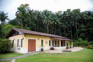 una pequeña casa frente a un bosque de palmeras en Pousada Vilarejo do Quim en Tapiraí