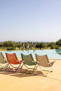 レイタニにあるAgua Green Resortのプールの前に座る芝生の椅子3脚
