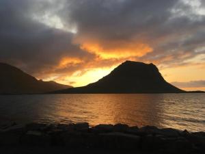 un coucher de soleil sur l'eau avec une montagne en arrière-plan dans l'établissement The Cat’s Cradle, à Grundarfjörður