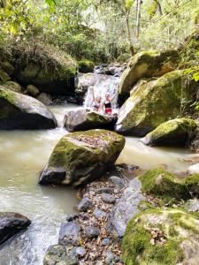 two people sitting on rocks in a stream at Macheta Climbing House in Machetá