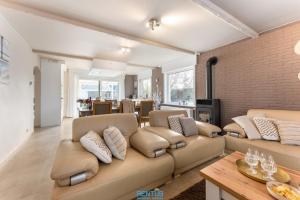 a living room with a couch and a brick wall at Villa T’Uzetje – villa with pool in Oostduinkerke in Oostduinkerke