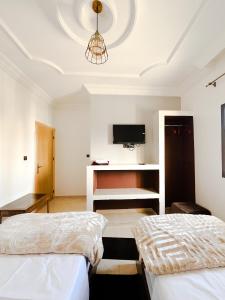a bedroom with two beds and a tv on the ceiling at Hotel Ahmed Ali in Dakhla